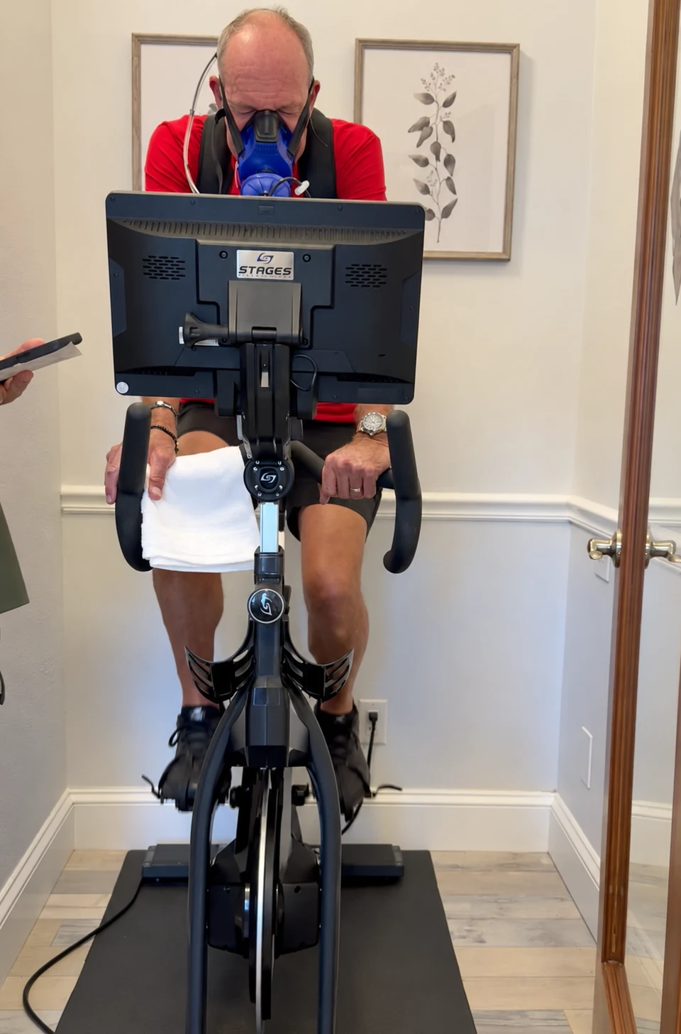 A guest in a red shirt completing a PNŌĒ exercise assessment on the studio bike